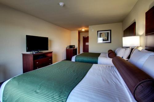 a hotel room with two beds and a flat screen tv at Cobblestone Inn & Suites - Rugby in Rugby