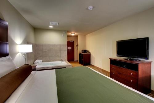 a hotel room with a tv and a bed at Cobblestone Inn & Suites - Rugby in Rugby