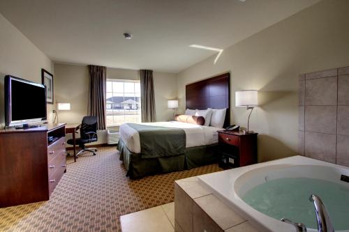 um quarto de hotel com uma cama e uma banheira em Cobblestone Inn & Suites - Rugby em Rugby