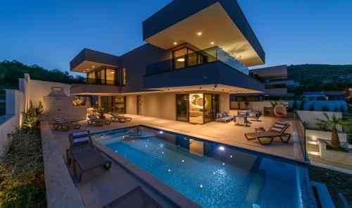 a large house with a swimming pool in front of it at Villas Lucy - 1 Lemon -outdoor pool , 2 Cherry-indoor pool and 3 Plum-outdoor pool in Marina