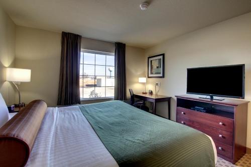 a hotel room with a bed and a flat screen tv at Cobblestone Inn & Suites - Harvey in Harvey