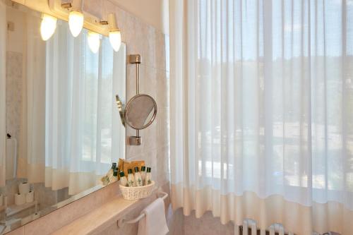 baño con espejo y cortina de ducha en Hotel Plaza, en Tabiano