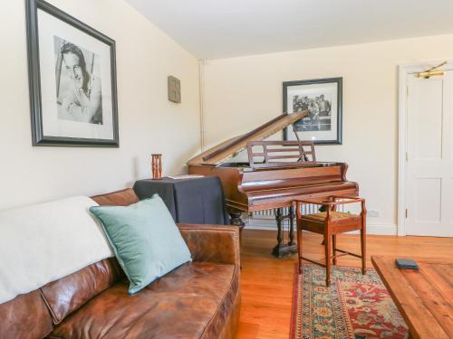 a living room with a couch and a piano at Groomes Country House in Bordon