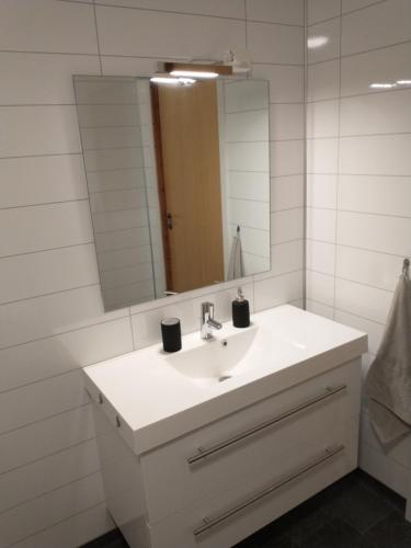 y baño con lavabo blanco y espejo. en Leinastova, en Sandshamn