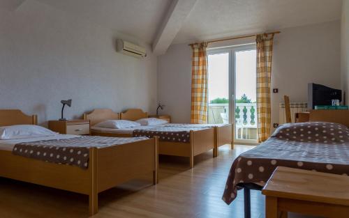 a room with three beds and a large window at Guesthouse Palombaro in Umag
