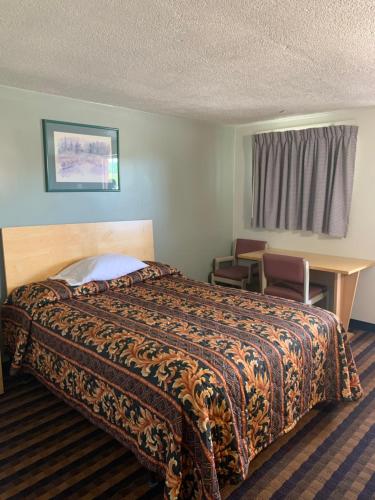 Newton FallsにあるBudget Lodge Newton Fallsのベッドとデスクが備わるホテルルームです。