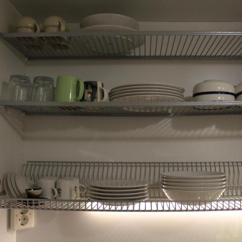 a kitchen shelf with plates and dishes on it at Bright star apartament Siilinjärvi in Siilinjärvi