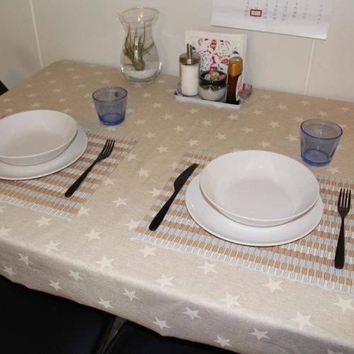 a table with two white plates and silverware on it at Bright star apartament Siilinjärvi in Siilinjärvi