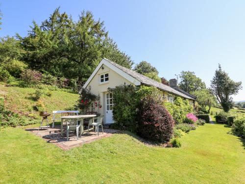 a small white cottage with a table and chairs in a yard at Dolgenau Hir - The Barn in Trefeglwys
