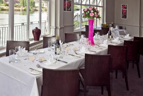 a dining room with a long table with white tables and chairs at Sunday London Staines-upon-Thames Heathrow T5 in Staines