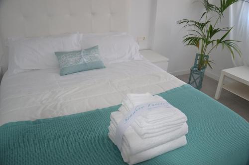 un letto bianco con sopra asciugamani di La Perla de Sunset Beach a Corralejo