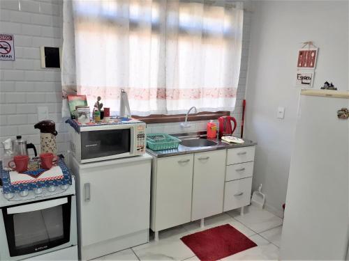 a small kitchen with a microwave and a sink at loft harmonia in Blumenau