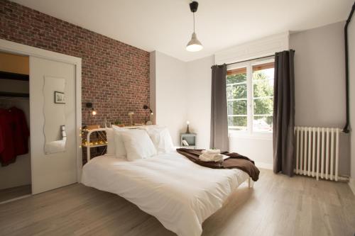 - une chambre avec un grand lit blanc et un mur en briques dans l'établissement #LIndustrioChampetre Free Parking, Bien Situé, Spacieux, Proche Clinique, à Rouen