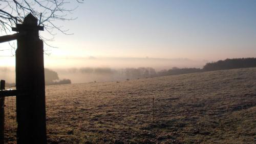 a foggy field with a wooden pole in the foreground at La Gaucherie aux Dames in Vihiers