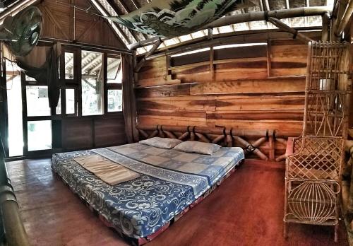 a bed in a room with a wooden wall at Harry's Ocean House Watukarung Homestay in Kalak