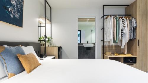 a bedroom with a white bed and a bathroom at Oaks Cairns Hotel in Cairns