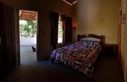 a bedroom with a bed and a cat looking out the door at Rancho Colcha de Retalho in Caucaia