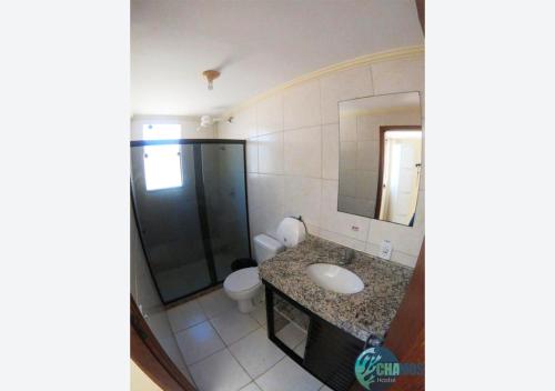 a bathroom with a sink and a toilet and a mirror at Chamos Hostel Cultural in Arraial do Cabo