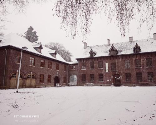 a large brick building with snow on the ground at Het Domherenhuis B&B, Restaurant Calice in Heusden - Zolder