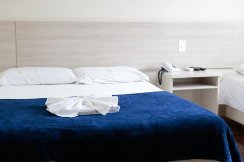 a hotel room with a bed with a blue blanket at Soratur Hotel & Coworking in Criciúma
