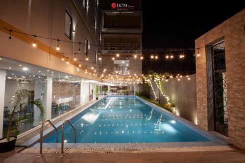 una piscina en un edificio por la noche con luces en @HOM Premiere Timoho, en Yogyakarta
