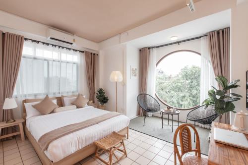 a bedroom with a large bed and a large window at Muan Hotel in Chiang Mai