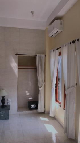 a room with white curtains and a window at Tasik Dumun Homestay and Waroeng in Amed