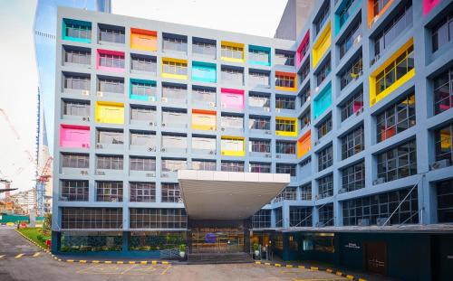 a tall building with colorful windows and a building at Hotel Olympic Malaysia Kuala Lumpur in Kuala Lumpur