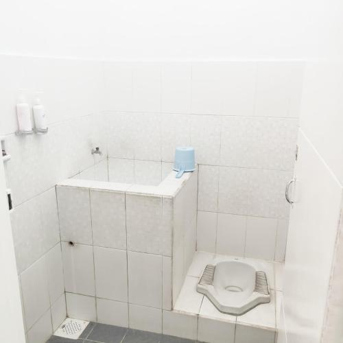 a white tiled bathroom with a toilet in it at Hotel Syariah Cordova in Tangkil