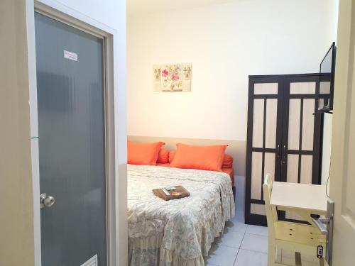 a small bedroom with a bed with orange pillows at Delta Inn Bogor Syariah for Indonesian Only in Bogor