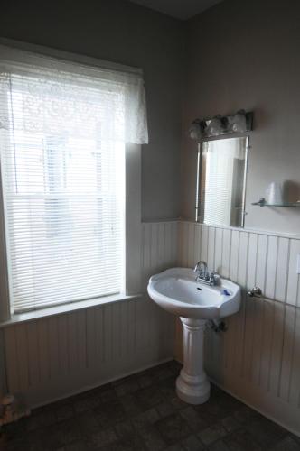 a white bathroom with a sink and a window at Hotel Coolidge in White River Junction