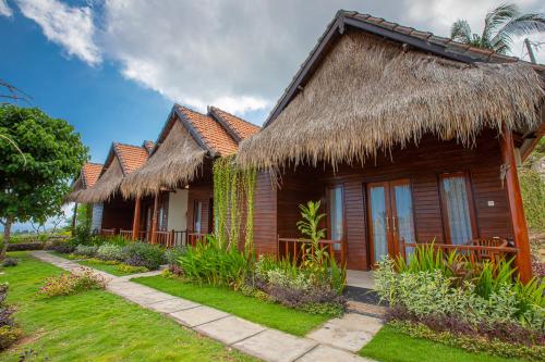 a row of cottages with a grass roof at Abian Selumbung Bungalow in Nusa Penida
