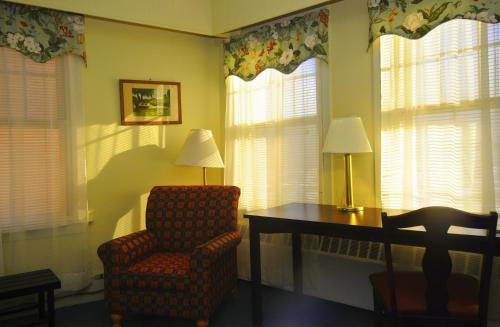 a room with a chair and a desk and windows at Hotel Coolidge in White River Junction