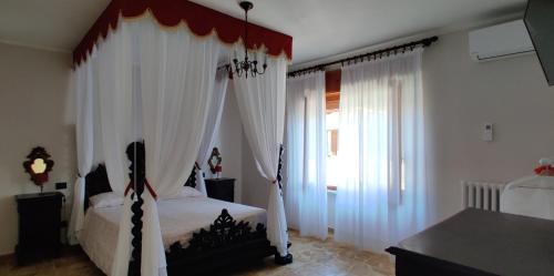 a bedroom with a canopy bed with white curtains at Cà ed Michel in Neviglie