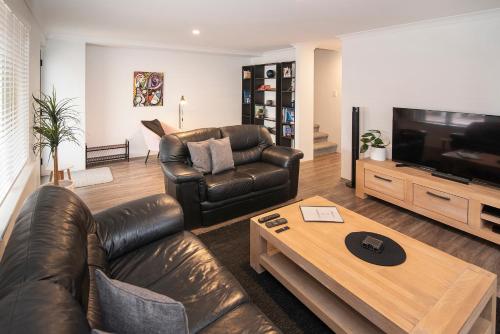 a living room with a leather couch and a television at @WinenWaves Margaret River in Margaret River Town