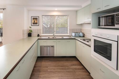 a kitchen with white cabinets and a sink at @WinenWaves Margaret River in Margaret River Town