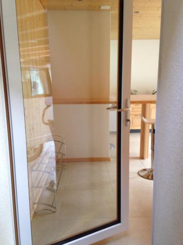eine Glasschiebetür mit einem Stuhl in einem Zimmer in der Unterkunft 2-Zimmer Ferienwohnung,Parterre,Sitzplatz,Garage in Adelboden