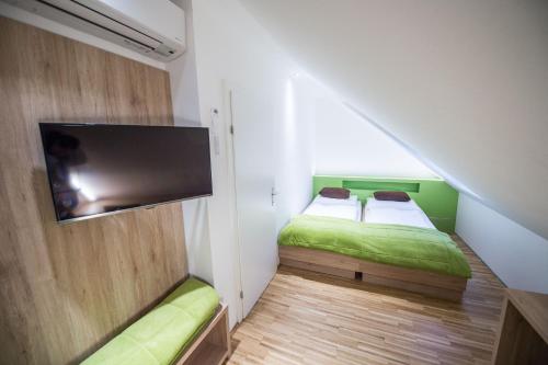 a small bedroom with two beds and a flat screen tv at Hotel Restaurant Meyer in Kalsdorf bei Graz