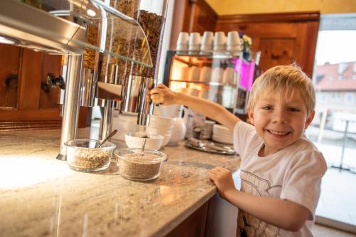 a young boy standing at a counter in a kitchen at Hotel Restaurant Meyer in Kalsdorf bei Graz