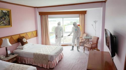 two doctors in a hotel room with a bed and a window at Viang Tak Riverside Hotel in Tak