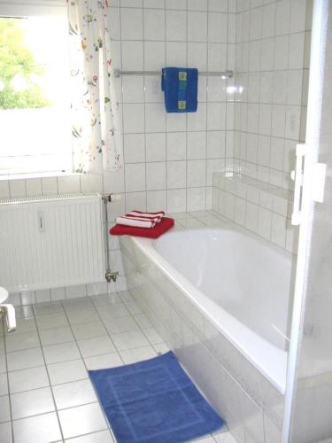 a white bath tub in a white tiled bathroom at Ferienhof Schwäbe in Lommatzsch