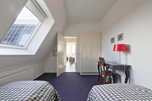 een zolderkamer met een bed, een bureau en een raam bij Residence de L'Europe - Baddomburg in Domburg