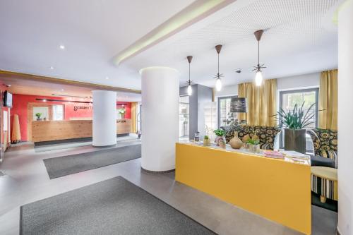 a lobby with white columns and a yellow counter at Hotel Grauer Bär in Sölden