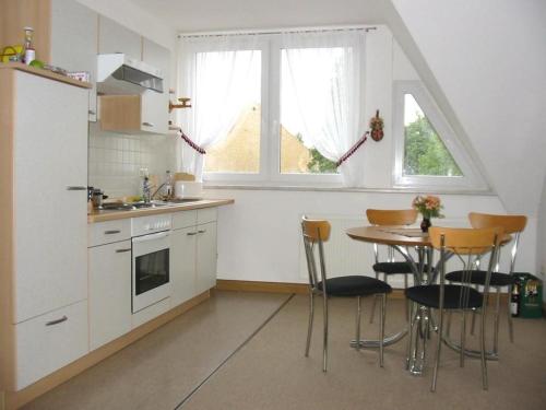 a kitchen with a table and chairs and a kitchen with white cabinets at Ferienhof Schwäbe in Lommatzsch