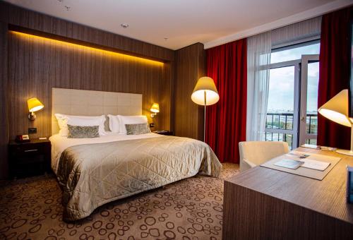 een hotelkamer met een groot bed en een bureau bij Domina Hotel Novosibirsk in Novosibirsk