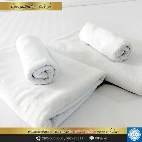two rolls of white towels sitting on top of a bed at The Kiri Resitel in Phetchaburi