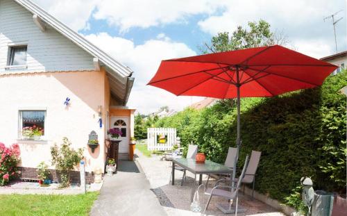una mesa con una sombrilla roja delante de una casa en Ferienwohnung Winterstetter Am Waldglasgarten en Riedlhütte