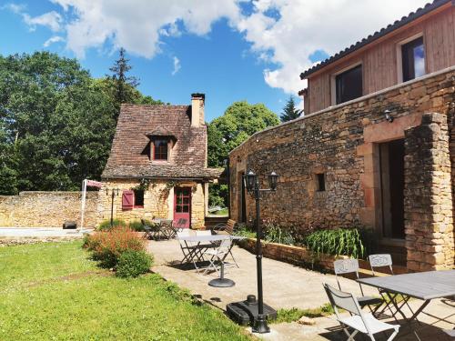 a stone house with a table and chairs in front of it at Gîte Les Combes Montignac Lascaux in Montignac