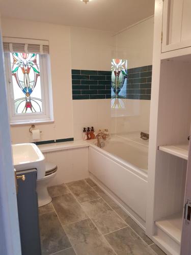 a bathroom with a tub and a toilet and a sink at Rosehip Cottage in Somerton