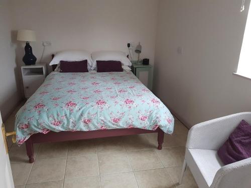 a bedroom with a bed and a chair at Rosehip Cottage in Somerton